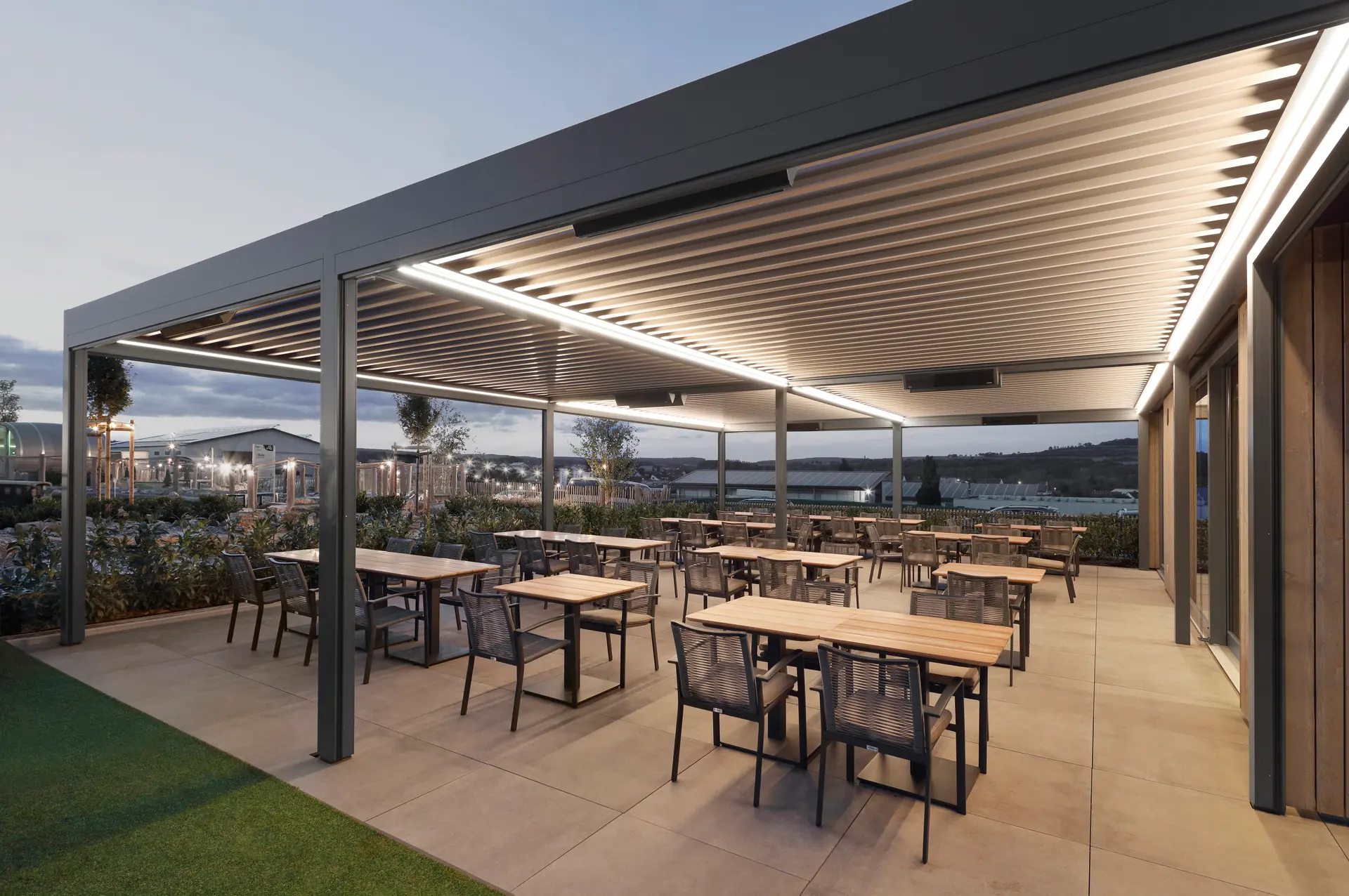 Stimmungsvolle LED-Beleuchtung für Markise Zusammenhängende Lamellendächer als Verschattung über der Terrasse eines Restaurants